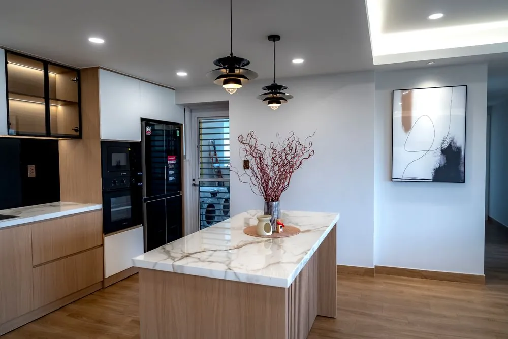 A modern kitchen with a stone island and warm lighting